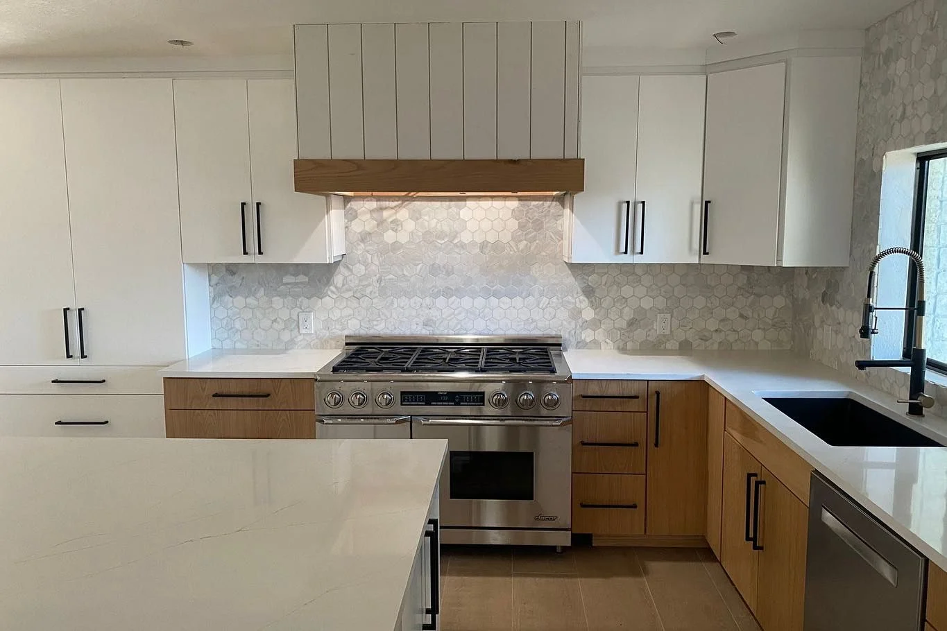 Modern kitchen with white and wood cabinetry, marble hexagon backsplash, stainless steel range, and quartz counters