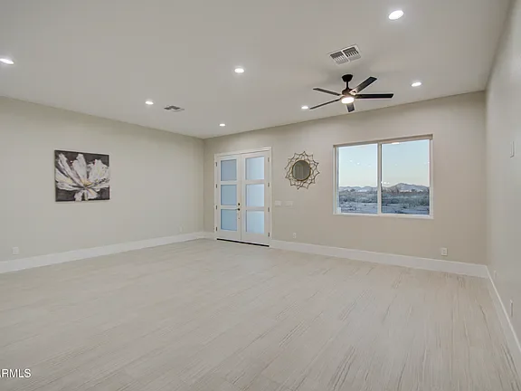 Bright master bedroom with light wood flooring, recessed lighting, French doors, and large windows