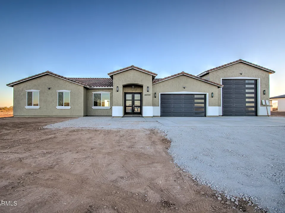 New stucco home with metal roof, contemporary garage doors, and concrete driveway
