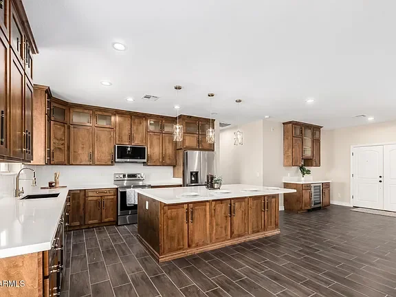 Custom wood kitchen cabinets with white quartz countertops, center island, and stainless steel appliances