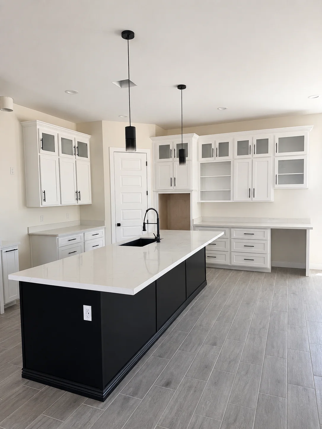 White cabinetry kitchen with black island, white quartz counters, and gray tile flooring