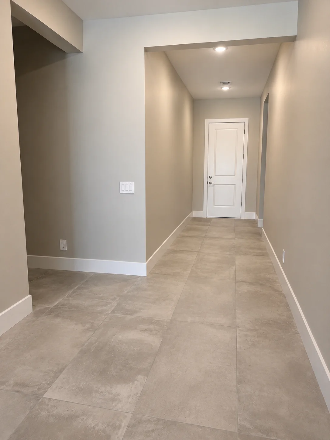 Finished basement hallway with tile flooring, painted walls, recessed lighting, and white interior door