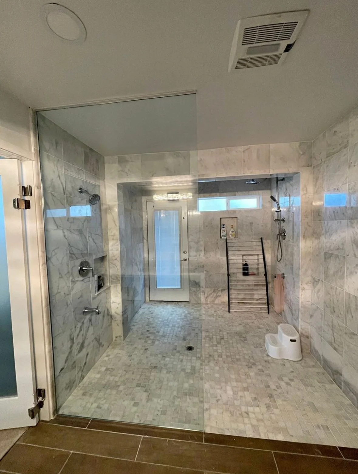 Marble tile walk-in shower with frameless glass doors and dual showerheads