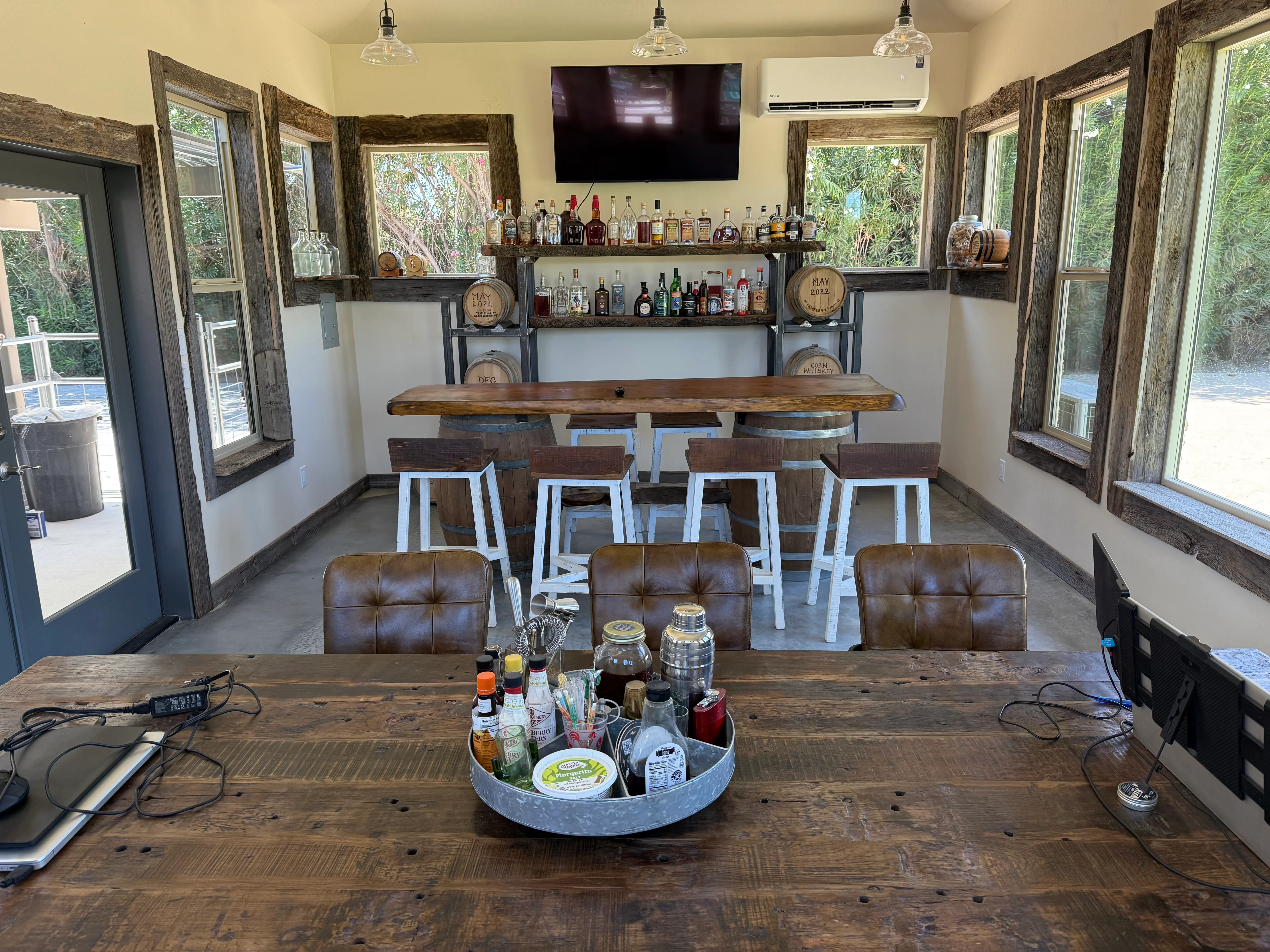 Rustic bar interior with live-edge wood counter, tiered shelving, reclaimed wood frames, and leather seating