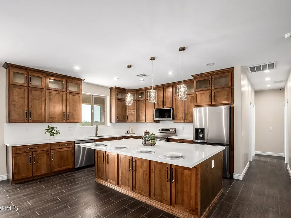 Custom wood kitchen cabinets, white quartz island countertop, stainless steel appliances, pendant lights