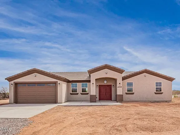 New stucco home with gabled rooflines, two-car garage, and concrete driveway