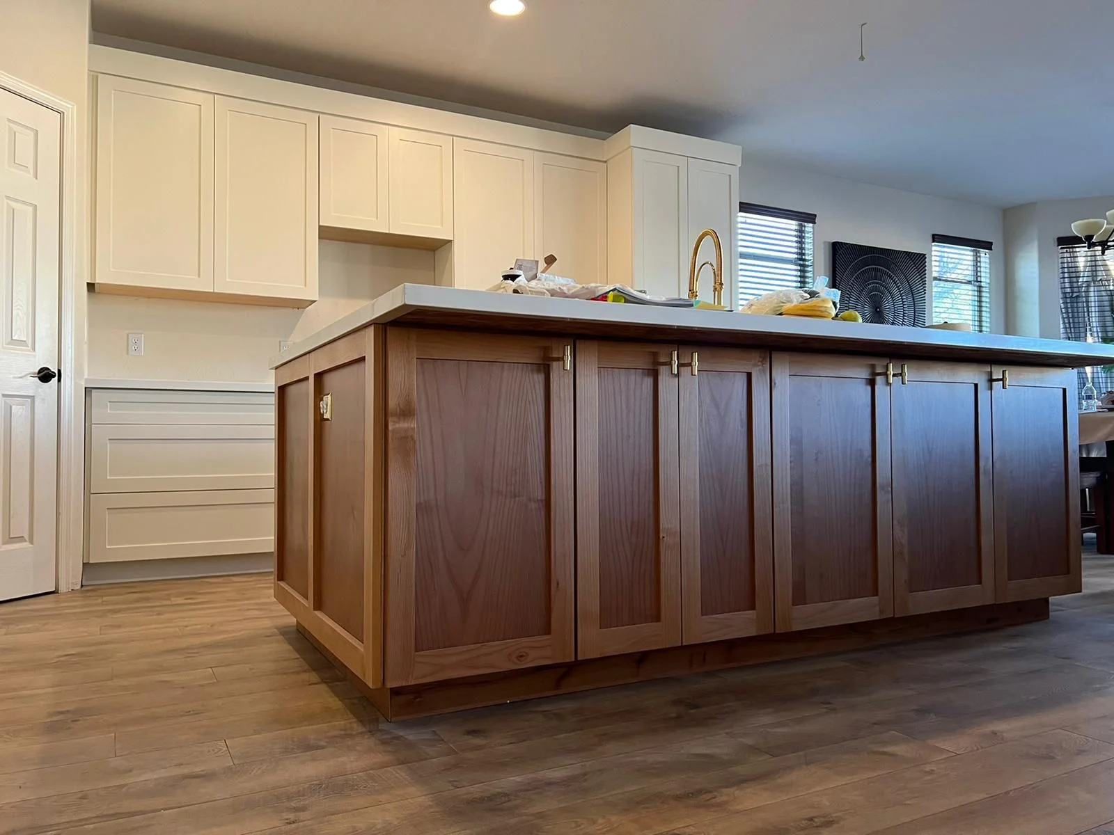 Two-tone kitchen with cream upper cabinets, dark wood island, waterfall countertop, and hardwood floors
