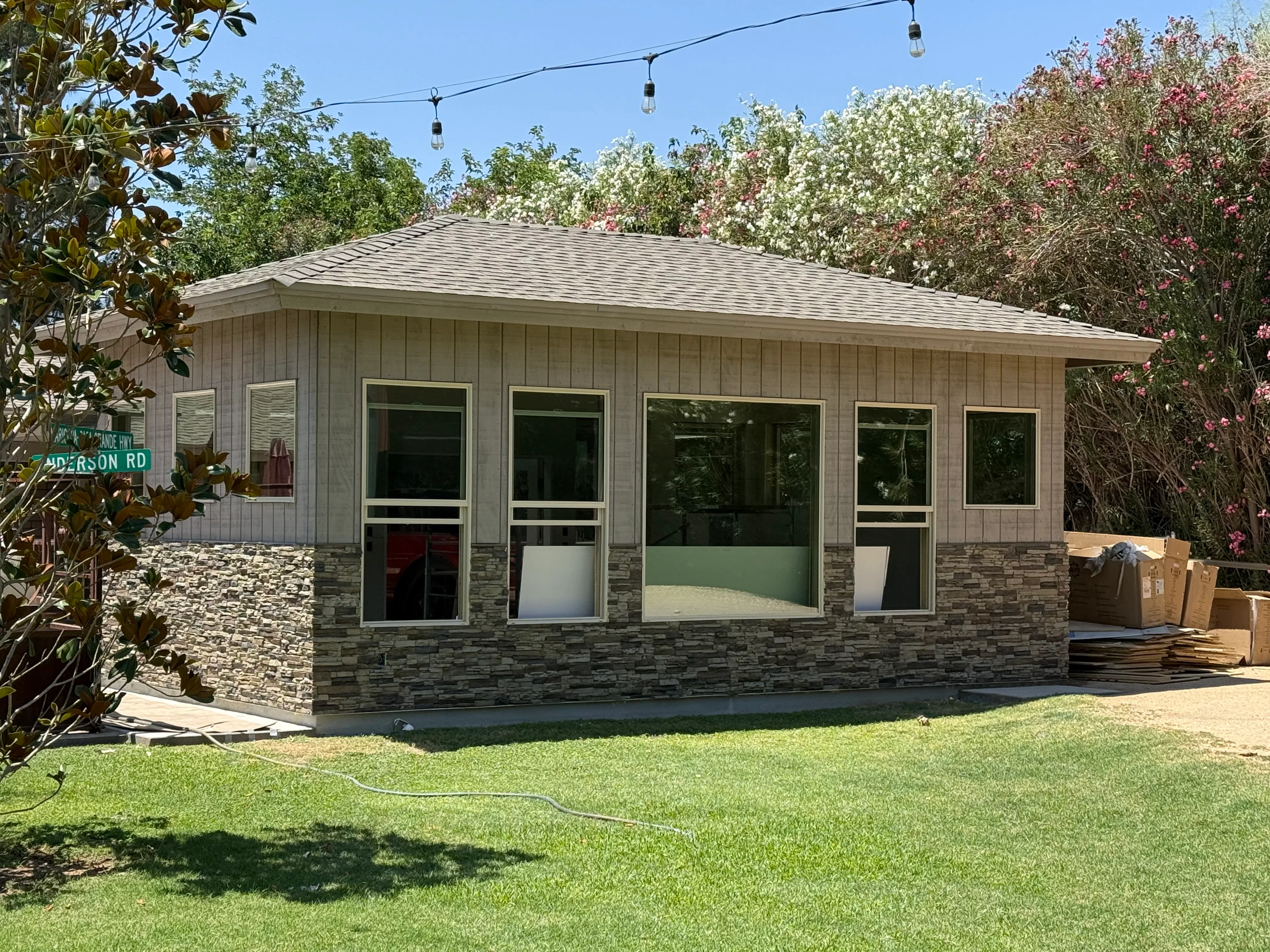 New casita with stone veneer base, board siding, multiple windows, and pitched roof