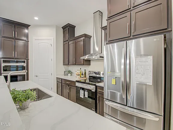 Modern kitchen with dark wood cabinets, white quartz counters, stainless steel appliances
