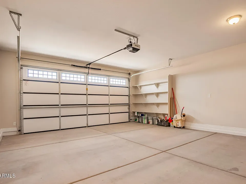New garage with aluminum overhead door, concrete floor, and white shelving installation